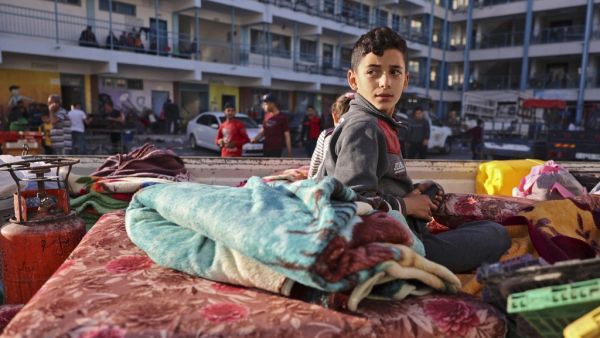 A Palestinian boy who fled his home due to Israeli air and artillery strikes sits on a mattress outside at a school hosting refugees in Gaza city, on May 14, 2021, as cross-border violence between the Israeli military and Palestinian militants continues in the Gaza Strip