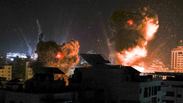Explosions light-up the night sky above buildings in Gaza City as Israeli forces shell the Palestinian enclave, early on May 18, 2021. Israeli jets kept up a barrage of air strikes against the Palestinian enclave of Gaza as a week of violence that has killed more than 200 people pushed world leaders to step up mediation. MAHMUD HAMS / AFP Death toll tops 212 in Gaza Strip