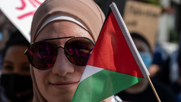 A woman holds the flag of Palestine next to her face during a pro-Palestine protest 