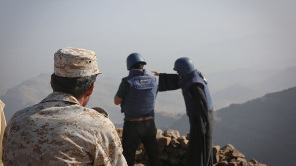 A Yemeni soldier looks at two journalists reporting the event 