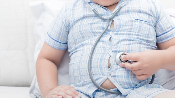 Obese fat boy check stomach by stethoscope.