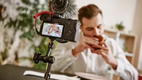 Close up of digital camera screen with male food blogger eating a sandwich while recording video for his vlog.