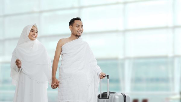 Muslim couples wife and husband wearing white traditional clothes for Ihram ready for Hajj walk in the airport