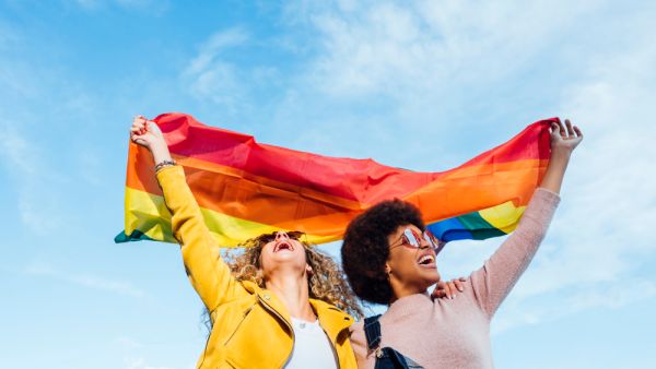 Two women friends hanging out in the city waving LGBT with pride flag