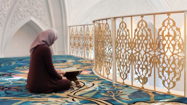 A young Muslim woman reads the Quran in the beautiful mosque