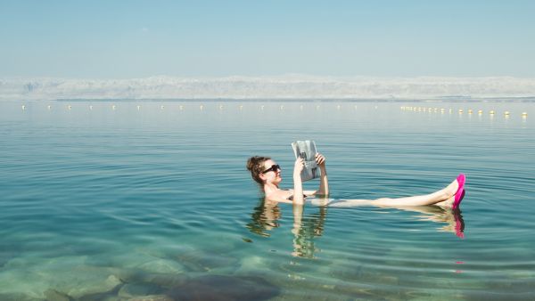 Girl reading newspaper floating on surface Dead Sea 
