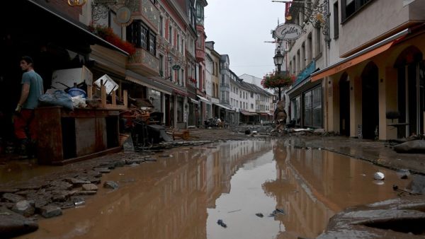 A resident stands next to damaged furnitures in a flooded street in Bad Neuenahr-Ahrweiler, western Germany, on July 15, 2021. German authorities said late July 15, 2021 that at least 58 people had likely died in massive storms and flooding in the country's west, an increase on the earlier toll of 45 dead