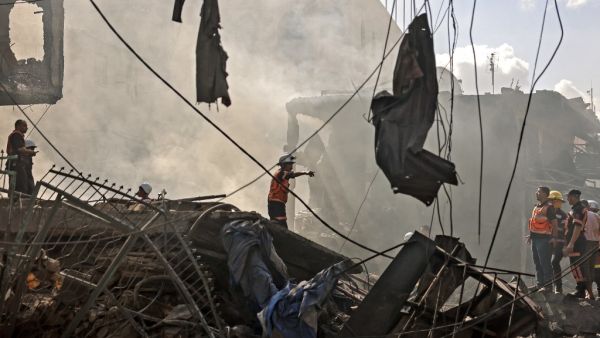 Palestinian rescuers and firefighters gather at the scene of a blast in Gaza City, the cause of which has not yet been determined