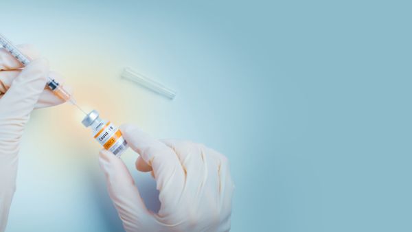 Hand of doctor use a needle syringe to take a shot from vaccine vial