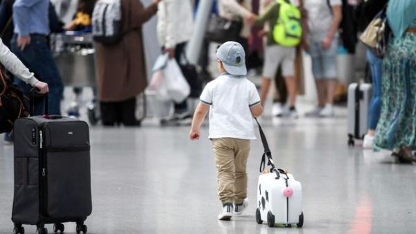 A little boy walks with his suitcase