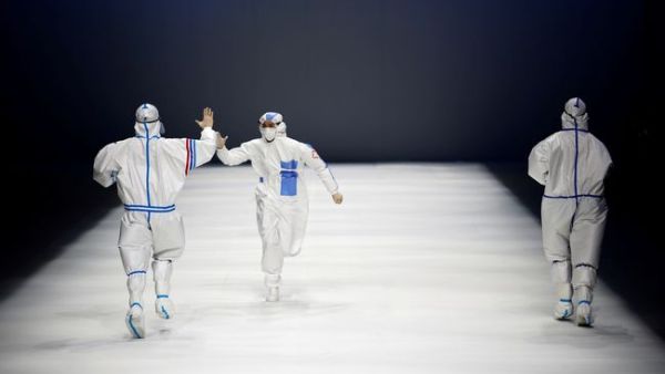 Models wearing outfits inspired by healthcare workers walk down the runway as part of the 'Heroes in Harm's Way' collection during the China Fashion Week in Beijing.