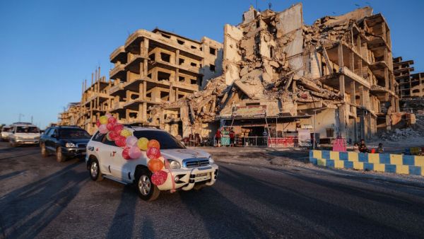 A wedding convoy drives past Abu Ali's cafe