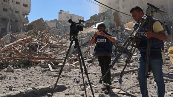  Journalists stand next to the rubble of Al-Jalaa Tower in Gaza 