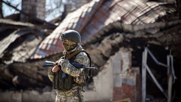 A Russian soldier stands in front of an apartment building on April 11, 2022, in Volnovakha in the Donetsk region, which the Russian authorities say was damaged by Ukrainian shelling. The picture was taken during a trip organized by the Russian military. (Photo by Alexander NEMENOV / AFP) Russian shelling destroys residential building in Bakhmut