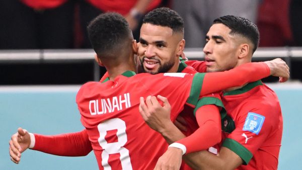 Morocco's forward #19 Youssef En-Nesyri (C) celebrates with Morocco's midfielder #08 Azzedine Ounahi (L) and Morocco's defender #02 Achraf Hakimi after he scored his team's first goal during the Qatar 2022 World Cup quarter-final football match between Morocco and Portugal at the Al-Thumama Stadium in Doha on December 10, 2022. (Photo by Kirill KUDRYAVTSEV / AFP)