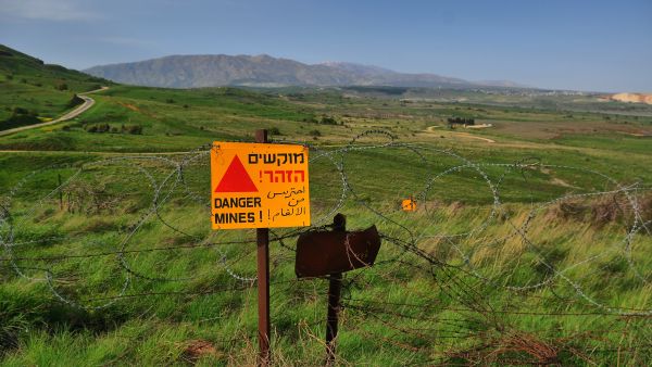 علامة تحذير صفراء من خطر الألغام على سياج من الأسلاك الشائكة في مرتفعات الجولان المحتل