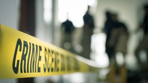 crime scene tape with blurred forensic law enforcement background in cinematic tone and copy space