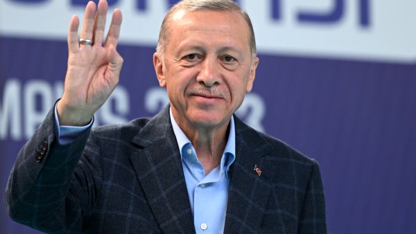 (Photo by OZAN KOSE / AFP) Erdogan distributes money inside polling station