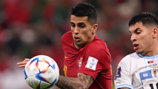 Portugal's defender #20 Joao Cancelo (L) and Uruguay's defender #16 Mathias Olivera fight for the ball during the Qatar 2022 World Cup Group H football match between Portugal and Uruguay at the Lusail Stadium in Lusail, north of Doha on November 28, 2022. (Photo by Kirill KUDRYAVTSEV / AFP)