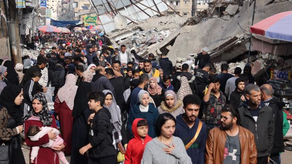 Crowds of people walk past destroyed buildings in the southern Gaza Strip city of Khan Yunis on November 28, 2023. (Mohammed Abed/ AFP)