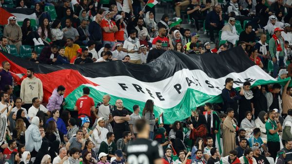 علم فلسطين يرفرف خلال مباراة إيران وفلسطين (Photo by KARIM JAAFAR / AFP)