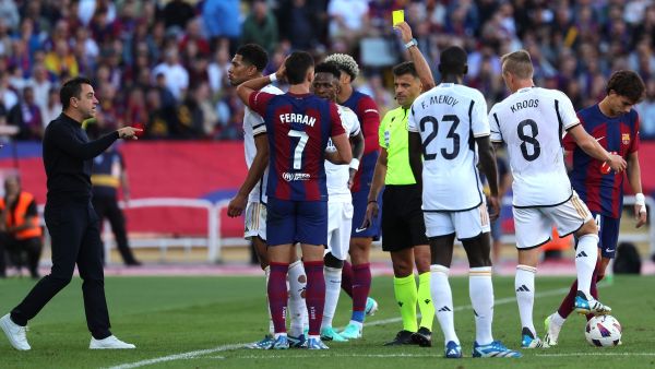 Barcelona's Spanish coach Xavi (L) reacts to the presentation of a yellow card by Spanish referee Gil Manzano to Barcelona's Spanish forward #07 Ferran Torres for fouling Real Madrid's Brazilian forward #07 Vinicius Junior (4L) during the Spanish league football match between FC Barcelona and Real Madrid CF at the Estadi Olimpic Lluis Companys in Barcelona on October 28, 2023. (Photo by LLUIS GENE / AFP)