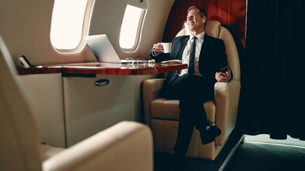 Senior businessman in suit flying in private jet