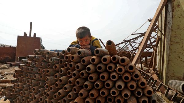 طفل سوري يجلس فوق أسلحة استعملها النظام السوري في ضرب أهداف مدنية. أرشيف. وكالة الصحافة الفرنسية.