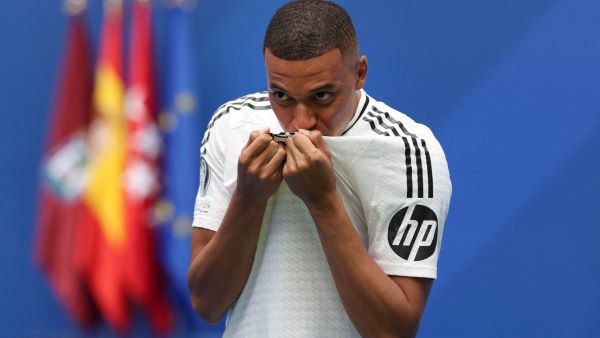 مبابي يقبل قميص ريال مدريد (Photo by Pierre-Philippe MARCOU / AFP)