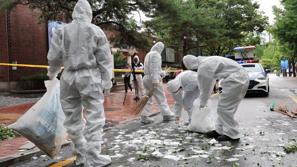 South Korean officials clean up the contents of a trash-carrying balloon sent by North Korea after it landed on a street in Seoul on July 24, 2024. (Photo by YONHAP / AFP) South Korea