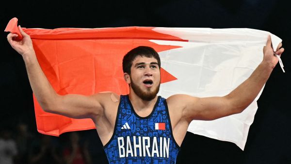 Bahrain's Akhmed Magomed O Tazhudinov celebrates his win with his national flag after beating Georgia's Givi Matcharashvili in their men's freestyle 97kg wrestling final match at the Champ-de-Mars Arena during the Paris 2024 Olympic Games, in Paris on August 11, 2024. (Photo by Punit PARANJPE / AFP)
