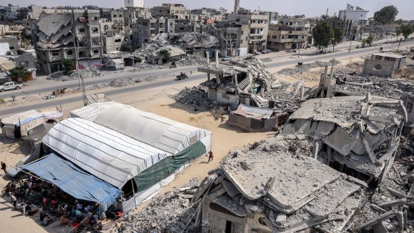 Muslim worshippers perform the weekly Friday prayers in a tent enclosure by destroyed buildings in Khan Yunis in the southern Gaza Strip on October 18, 2024 amid the ongoing war in the Palestinian territory between Israel and Hamas. (Photo by BASHAR TALEB / AFP)