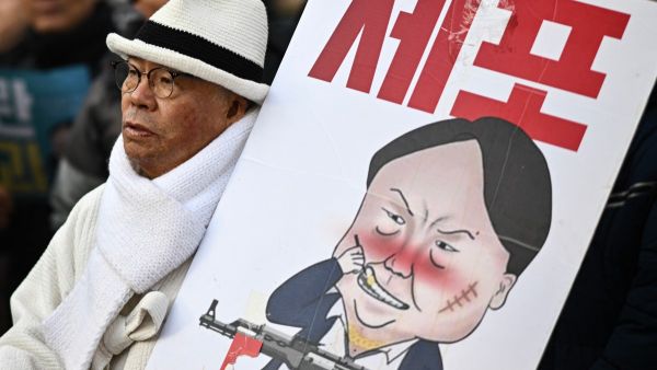 A man carrying a placard with a comic depicting South Korea's impeached president Yoon Suk Yeol marches during an anti-Yoon rally in Seoul on January 3, 2025. 