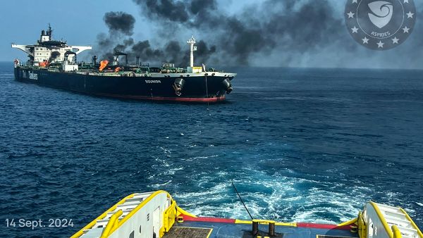 TOPSHOT - This handout picture provided by EUNAVFOR ASPIDES on September 15, 2024, and dated September 14, shows a vessel with a rope extended toward the Greek-owned oil tanker Sounion as smoke and fire billows from it, off the coast of Hodeida in the Red Sea A Greek defence ministry source told AFP on September 14, that the Sounion was being towed northward under military escort in a salvage operation. (Photo by EUNAVFOR ASPIDES / AFP) British ship attacked by missiles off Yemen’s coast