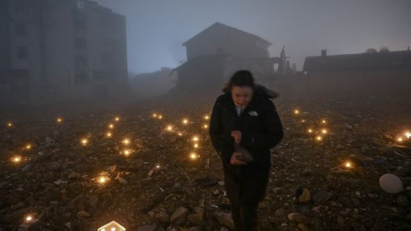 A woman leaves a candle at the site of a demolished building during the first anniversary of the earthquake, in Antakya on February 6, 2024. (Photo by Ozan KOSE / AFP) earthquake Turkey
