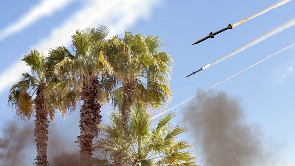 صواريخ باليستية في السماء على خلفية أشجار النخيل، مع آثار إطلاق الصواريخ…