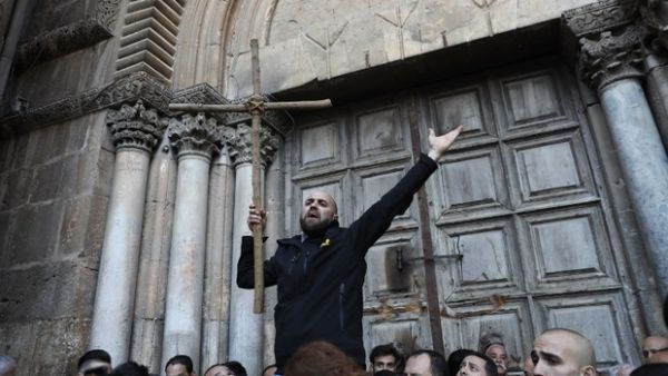 A Palestinian man holds a cross during a protest in front of the Church of the Holy Sepulchre in Jerusalem (AFP/File Photo)