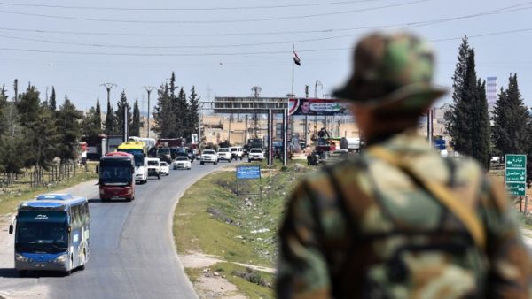 A convoy transporting Jaish al-Islam fighters and their families from the former bastion's main town of Douma arrives at the entrance to the northern Syrian city of Aleppo after being evacuated from the last rebel-held pocket in Eastern Ghouta on Apr. 3, 2018. 
(George OURFALIAN / AFP)