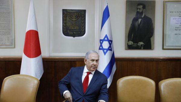 Israeli Prime Minister Benjamin Netanyahu sits in conference room before flags of Japan (L), Israel (C), and a portrait of Theodor Herzl (seen as "Visionary of the Jewish State" and founder of modern Zionism) at the PM office ahead of his meeting with his Japanese counterpart in Jerusalem on May 2, 2018. 
(Abir SULTAN / POOL / AFP)