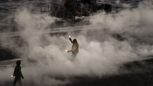 A crew member of U.S. aircraft carrier USS Harry S Truman reacts after the takeoff of an F18 Hornet fighter jet from the flight deck of the ship in the eastern Mediterranean Sea on May 8, 2018. The Harry S Truman carrier strike group on May 3, began air operations in support of Operation Inherent Resolve, conducting flight operations against ISIS targets in Syria. The strike group includes a guided-missile cruiser and four guided-missile destroyers. (Aris MESSINIS / AFP)