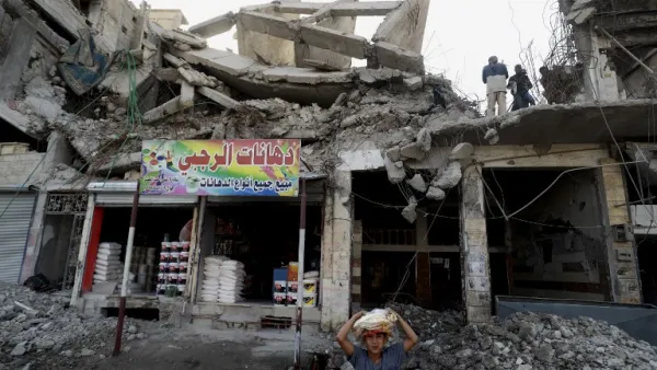 Labourers clear debris from a destroyed building in the Syrian city of Raqa (AFP)