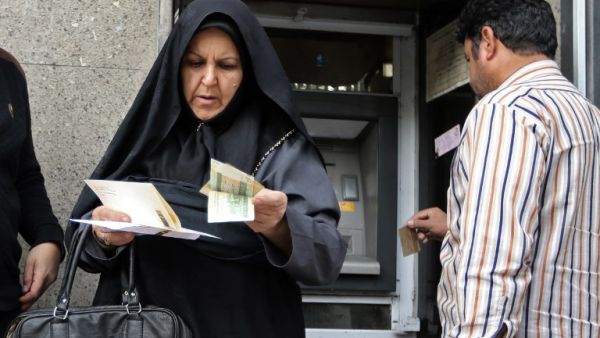 People withraw money from an automated teller machine in the Iranian capital Tehran's grand bazar on November 3, 2018 (AFP)