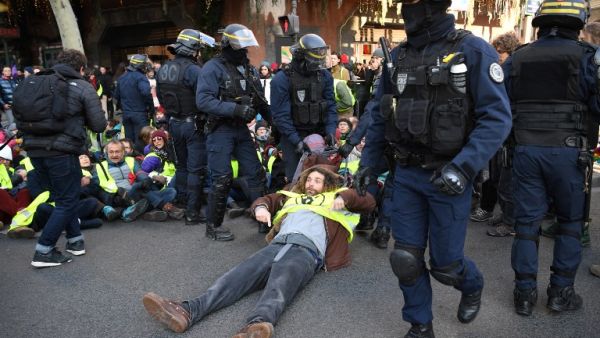 An activist of "Les amis de la terre" (Friends of the Earth) environmental NGO is evacuated by riot police during a demonstration outside the headquarters of French banking group Societe general to denounce its alleged support of fossil fuel inudstries 8 in Paris (AFP)
