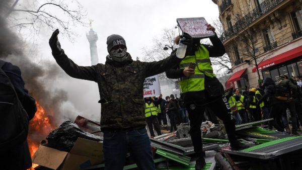 Protesters react as they face police at a barricade during an anti-government demonstration called by the "yellow vests"  (AFP)