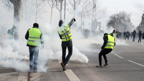 Protesters wearing a yellow vest throw back tear gas canisters to police officers near the National Assembly in Paris, on February 9, 2019. (AFP/ File)
