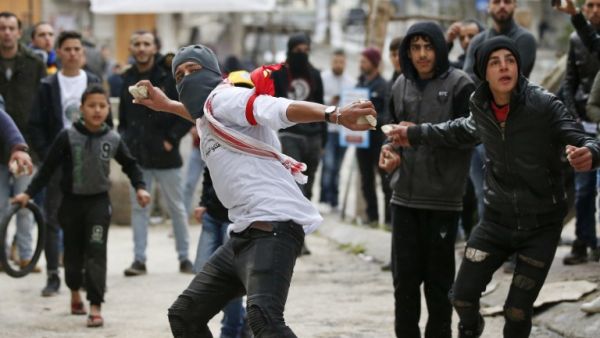 Palestinian protesters hurl stones at Israeli soldiers near a gate leading to Hebron's main al-Shuhada street. (AFP/ File Photo)