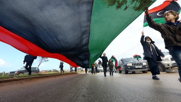 Libyans carry a giant national flag in the capital Tripoli during a celebration to mark the the upcoming eighth anniversary of the revolution which toppled strongman Moamer Kadhafi, on February 25, 2019. (AFP)