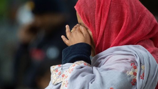 A Muslim woman weeps as she stands across the road from the Dean Street mosque when worshipers were gunned down in Christchurch  (AFP)