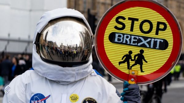A person dressed as an astronaught holding a school traffic crossing sign reading "Stop Brexit" joins a march and rally organised by the pro-European People's Vote campaign for a second EU referendum in central London (AFP)
