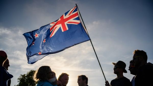 A man raises a New Zealand flag as he attends a vigil in memory of the twin mosque massacre victims in Christchurch (AFP)